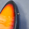 Close-up of sunburst electric guitar body edge with black finish and metal strap button on gray background