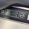 Digital scale display showing the weight of a guitar as 3.664 kilograms, with kg and lb conversion option and tare function visible.