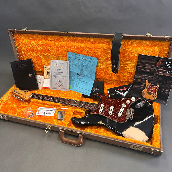 Fender custom shop vintage black distressed Stratocaster electric guitar with tortoiseshell pickguard in orange plush lined hard case, includes Fender certificate of authenticity, custom shop paperwork, and accessories.