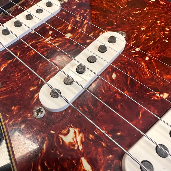 Close-up of electric guitar single-coil pickups and strings on a tortoise shell pickguard
