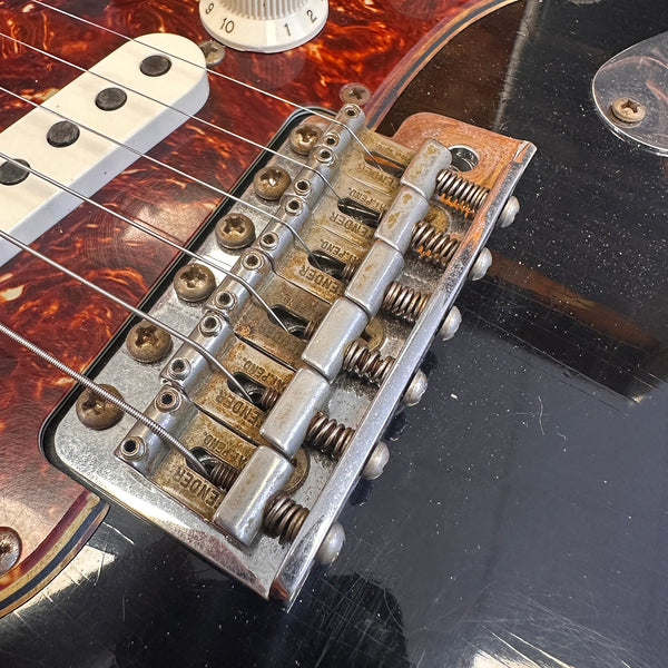 Close-up of vintage Fender electric guitar bridge and pickup with tortoiseshell pickguard and volume knob