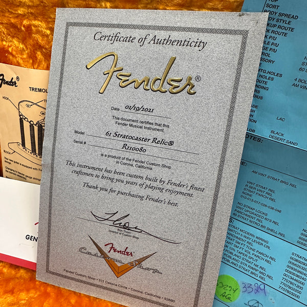 Certificate of Authenticity for a Fender 61 Stratocaster Relic guitar dated 01/19/2021 from Fender Custom Shop in Corona, California on an orange plush background with Fender tremolo and specification sheets.