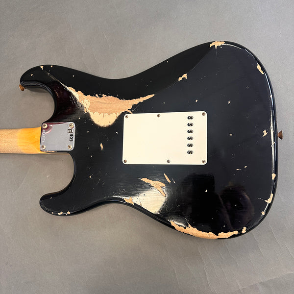Black electric guitar body with heavy paint wear and finish chips, showing natural wood underneath, vintage relic style