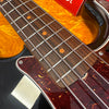 Close-up of four-string electric bass guitar fretboard and tortoiseshell pickguard on black body with yellow case lining background