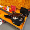 Fender electric bass guitar with black body and tortoiseshell pickguard in orange-lined case with Fender manuals and accessories