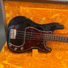 Black electric bass guitar with tortoiseshell pickguard and chrome bridge in an open orange velvet-lined hard case