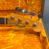Close-up of Fender Precision Bass headstock with tuning pegs and strings inside vintage orange plush guitar case