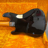 Glossy black electric guitar body with maple neck and four-screw neck plate inside bright orange textured guitar case interior