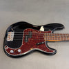 Black electric bass guitar with tortoiseshell pickguard and rosewood fretboard on gray background