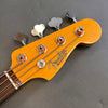 Close-up of Fender Precision Bass headstock with tuning pegs and strings on gray background