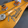 Close-up of Fender Precision Bass headstock with tuning pegs and strings on natural wood finish