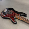 Black electric bass guitar with tortoiseshell pickguard and chrome hardware on gray surface