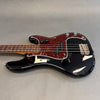 Black electric bass guitar with tortoiseshell pickguard and rosewood fretboard on gray background