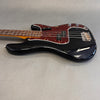 Black electric bass guitar with tortoiseshell pickguard and maple neck on gray background