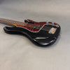 Black electric bass guitar with tortoiseshell pickguard and chrome knobs on gray background