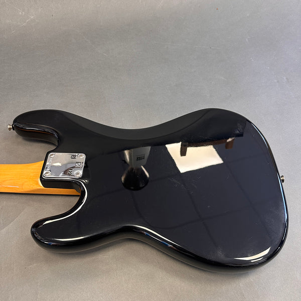 Black electric guitar body back with maple neck and chrome neck plate on gray background