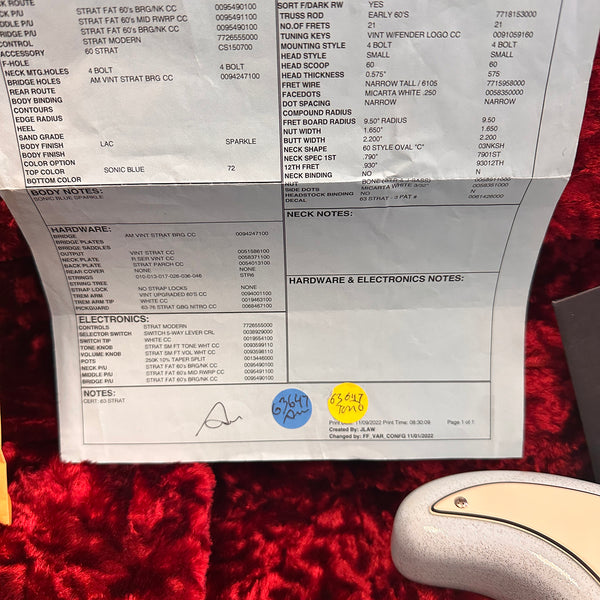 Close-up of Fender Stratocaster certificate showing specifications and hardware details for a Sonic Blue Sparkle Strat with 60s style vintage components and modern electronics.