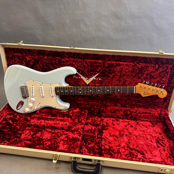 Fender Stratocaster electric guitar with silver sparkle finish inside vintage red plush lined beige hardshell case on gray background