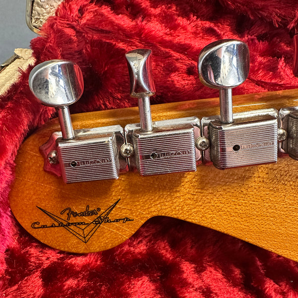 Close-up of vintage Fender Custom Shop guitar headstock with vintage-style tuning machines on red plush case interior