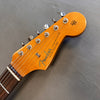 Close-up of Fender Stratocaster guitar headstock with tuning pegs and rosewood fretboard on gray background