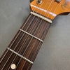 Close-up of Fender guitar headstock and rosewood fretboard with metal frets and steel strings on gray background