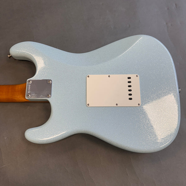 Back of light blue electric guitar with white tremolo cavity cover and four-screw neck plate on gray background