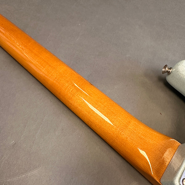 Close-up of glossy maple guitar neck wood texture with metal tuning machine on grey background