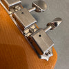 Close-up of vintage Kluson Deluxe guitar tuning pegs on natural wood headstock against gray background