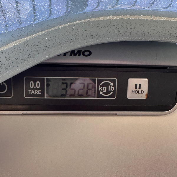 Digital scale showing guitar weight as 3.528 kilograms with part of light blue guitar body visible on top