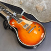 Sunburst electric guitar with humbucker pickups in open hard shell case on gray surface