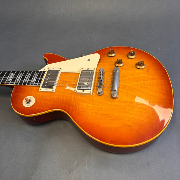 Sunburst electric guitar with dual humbucker pickups, cream pickguard, four control knobs, and tune-o-matic bridge on gray background