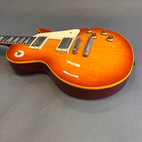 Sunburst electric guitar with dual humbucker pickups, cream pickguard, and four control knobs on gray background.