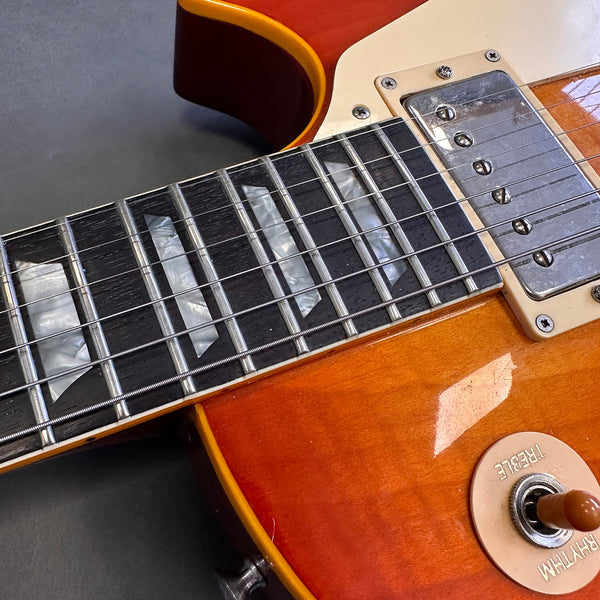 Close-up of vintage sunburst electric guitar neck, pearl trapezoid inlays, humbucker pickup, and rhythm-treble pickup selector switch on coffee house guitars product listing.