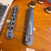 Close-up of electric guitar bridge and tailpiece with amber sunburst finish and amber tone control knobs