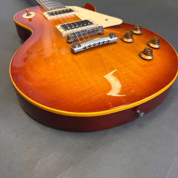 Close-up of sunburst electric guitar body with dual humbucker pickups, four control knobs, and chrome bridge on dark gray background