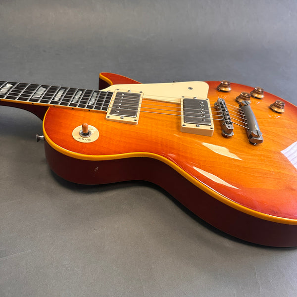 Cherry sunburst electric guitar with dual humbucker pickups and cream pickguard on gray background