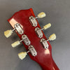 Close-up of vintage red guitar headstock with six white tuning pegs and chrome tuning machines on gray background