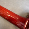 Close-up of glossy red guitar neck wood finish showing smooth texture and reflection on gray background