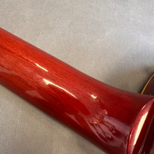 Close-up of glossy red guitar neck wood finish showing smooth texture and reflection on gray background