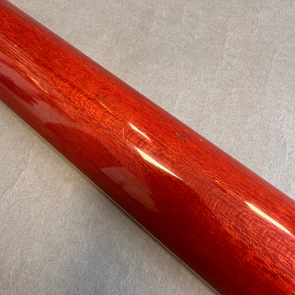 Close-up of glossy red wooden guitar neck with visible wood grain on gray background