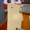 Close-up of vintage sunburst electric guitar body showing cream pickguard, humbucker pickup, and volume knob with wear details