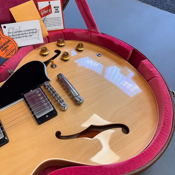 Gibson semi-hollow body electric guitar with natural finish in pink velvet-lined hard case, showing f-hole, bridge, pickups, and control knobs with authenticity cards and Gibson Vintage Tone Circuit tag.