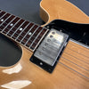 Close-up of natural wood finish electric guitar body with chrome humbucker pickup and rosewood fretboard on black background