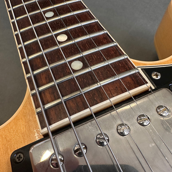Close-up of electric guitar fretboard and metal pickup with natural wood finish and detailed strings at Coffee House Guitars