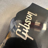 Close-up of black Gibson guitar headstock with mother-of-pearl Gibson logo inlay