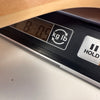 Close-up of a digital scale displaying the weight of a guitar part, showing 8 pounds and 0.5 ounces, with buttons for unit conversion between kilograms and pounds and a hold function.