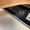 Close-up of a digital scale displaying the weight 3.644 pounds under the light wood body of an acoustic guitar, showing guitar weight measurement.