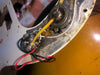 Close-up of vintage electric guitar wiring showing potentiometers, wires, and aged metal components inside guitar body cavity