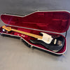 Black electric bass guitar with maple neck and white pickguard in open black hardshell case with red plush interior lining