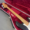 Fender Jazz Bass guitar with maple neck and black body in red velvet lined hard case on gray floor